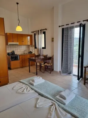 a living room with a table and a kitchen at Irida Apartments -EX BLAZIS HOUSE in Almirida