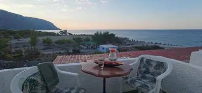 a table and chairs on a balcony with a view of the ocean at Paradise in Agia Roumeli