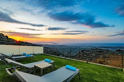 a patio with a view of the ocean at sunset at Villa Mari Chania, with private ecologic pool and amazing view! in Chania Town