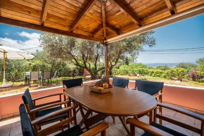 a wooden table and chairs on a porch with a table and umbrella at Villa Silva, Garden & Sea View, 3 BR, -10 min drive from center in Chania Town