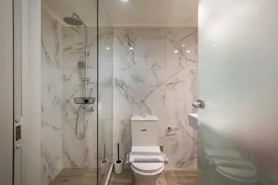 a bathroom with a toilet and a glass shower at Luxury Pearl, steps to the beach in Chania Town