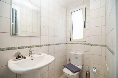 a white bathroom with a sink and a toilet at Villa Rodo in Pírgos Psilonérou