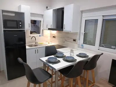 a kitchen with a table and chairs and a black refrigerator at Vrachakia Elegant in Ayiá