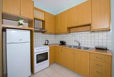 a kitchen with wooden cabinets and a white refrigerator at Peris #1 - Souda in Souda