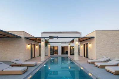 a swimming pool with lounge chairs in front of a building at Ikritis Villas in Chorafakia