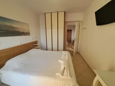 a bedroom with a white bed and a flat screen tv at Ocean View in Chania Town
