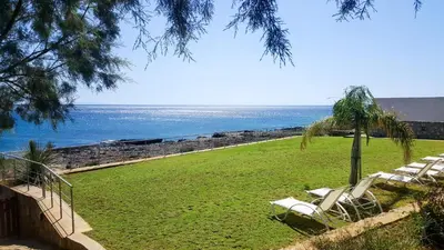 a group of chairs sitting on the grass near the ocean at Kritamos Beach Apartments in Frangokastello