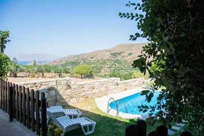 a swimming pool with two chairs next to a fence at VILLA MICHAELA in Gramvousá