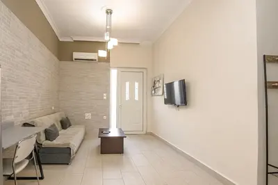 a living room with a couch and a tv on a wall at PLUS 2! in Chania Town