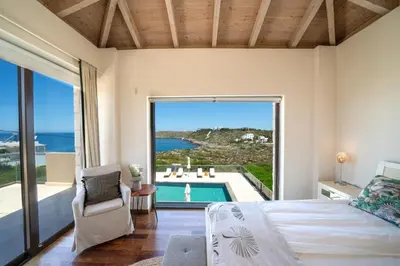 a bedroom with a bed and a view of the ocean at Villa Poseidon One - Sunset & Sea Front Villa in Chorafakia