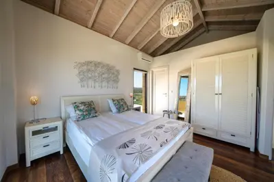 a bedroom with a bed and a chandelier at Villa Poseidon One - Sunset & Sea Front Villa in Chorafakia