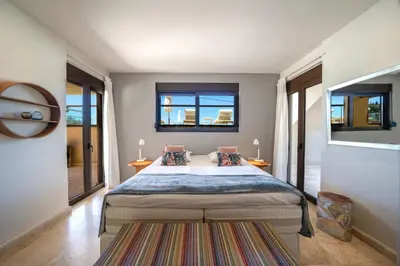 a bedroom with a large bed and two windows at Villa Poseidon One - Sunset & Sea Front Villa in Chorafakia