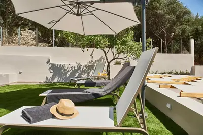 a table and chairs with an umbrella on the grass at El Platanias in Chania Town