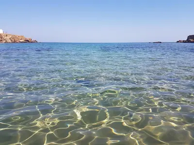 a large body of water with rocks in the background at Solis Occasum in Aghii Apostoli