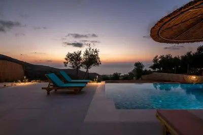 a pool with two blue lounge chairs and a sunset at Alma Natura Villas Falasarna- Avgerinos Villa in Falasarna