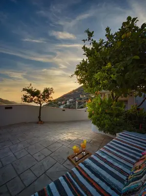 a patio with a tree and a table with oranges on it at West Crete House in Kámbos
