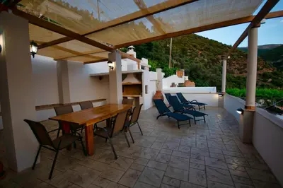a patio with a wooden table and chairs at West Crete House in Kámbos