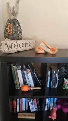 a book shelf with books and a welcome sign on it at Orea Kaliva in Sfinárion