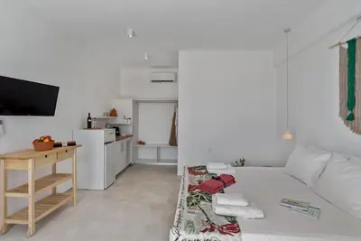a white room with a bed and a kitchen at Annassa Experience Suites 2' walk from Almyrida Beach in Almirida