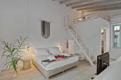 a white room with a bed and a staircase at Annassa Experience Suites 2' walk from Almyrida Beach in Almirida