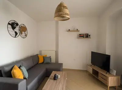 a living room with a gray couch and a tv at NEFELI APARTMENT CHANIA in Chania Town