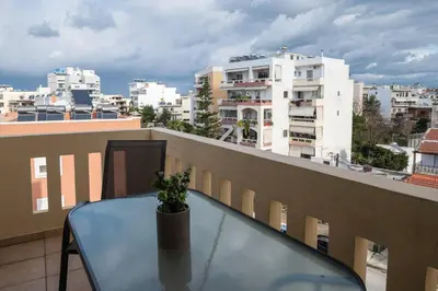 a glass table on a balcony with a view of buildings at NEFELI APARTMENT CHANIA in Chania Town