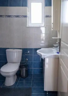 a bathroom with a toilet and a sink and a window at NEFELI APARTMENT CHANIA in Chania Town