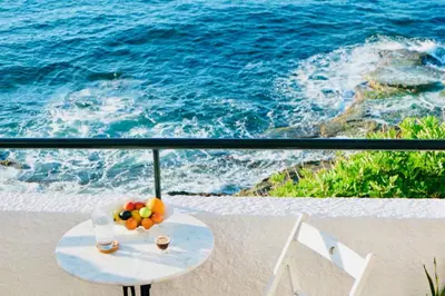 a table with fruit and drinks on a balcony overlooking the ocean at Elpida Seafront Paradise apartment in Crete in Chania Town