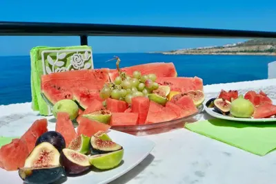 a table with a plate of fruit on a table at Elpida Seafront Paradise apartment in Crete in Chania Town