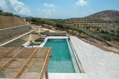 a swimming pool with chairs and umbrellas on a beach at Alma Natura Villas Falasarna - Aposperitis Villa in Falasarna