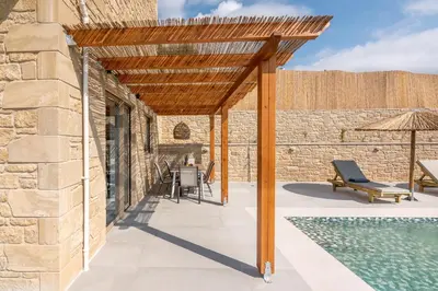 an outdoor patio with a wooden pergola and a swimming pool at Alma Natura Villas Falasarna - Aposperitis Villa in Falasarna