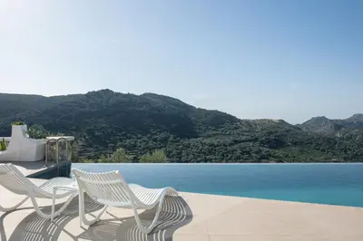 two white chairs sitting next to a swimming pool at Villa Anasa in Palaiochóra
