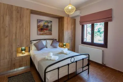 a bedroom with a bed with two lamps on it at Sounds Of The Mountain Chania in Varípetron