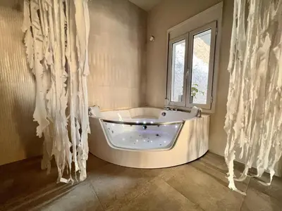 a bath tub in a bathroom with a window at Perla Coco Jacuzzi Suites in Chania Town