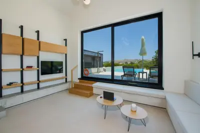 a living room with two tables and a large window at Fairytale Villas in Souda