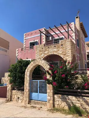 a building with a gate and flowers in front of it at Pink House in Palaiochóra