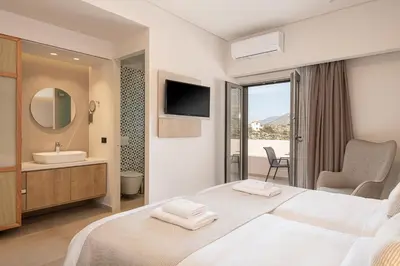 a bedroom with a bed and a sink and a mirror at Elafonisi Resort by Kalomirakis Family in Elafonisi