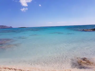 a beach with clear blue water and rocks at Elafonisi Vacation Blue Apartment in Agios Padeleimon