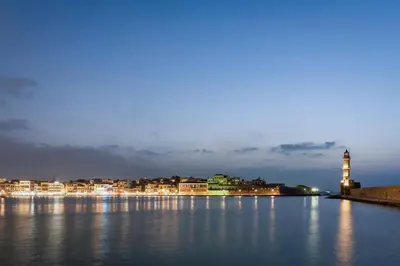 a large body of water with a lighthouse at night at Pasifai Residence - Chania old town in Chania Town