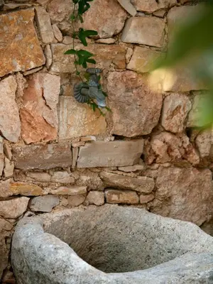 a stone wall with a bird feeder on it at The Garden of Zephyrus - East in Pithárion
