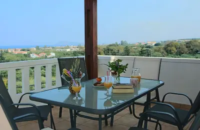 a glass table on a balcony with a view at Kouros Chania Villas in Maleme