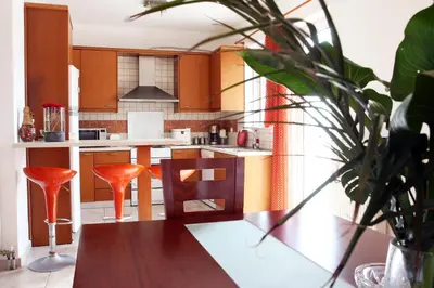 a kitchen with wooden cabinets and orange stools at Kouros Chania Villas in Maleme