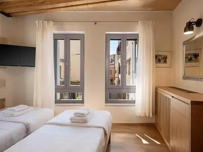 a bedroom with two beds and two windows at Austrinus house, luxury property for max. 5 persons in Chania Town