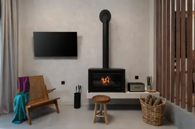a living room with a fireplace and a chair at KOEV slow living in Tsikalariá