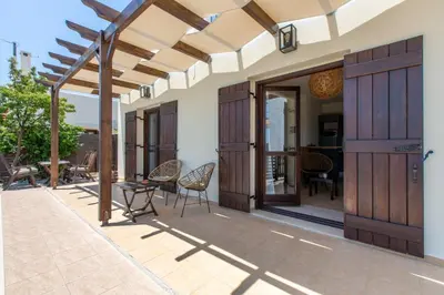 a patio with wooden doors and chairs and a table at Villa Henry Darmarohori in Darmarochori