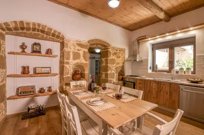 a kitchen with a wooden table and chairs in a room at Pool Villa Michail, in Kissamos! in Koukounará