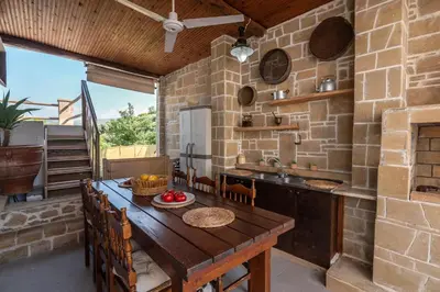 a kitchen with a wooden table and a stone wall at Pool Villa Michail, in Kissamos! in Koukounará
