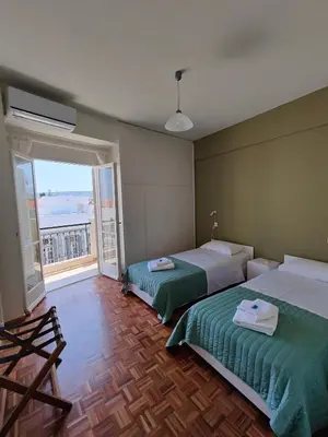 two beds in a room with a large window at Chania-Limani Splantzia-geada in Chania Town