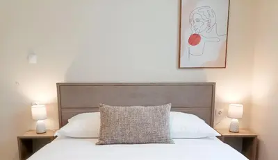 a bedroom with a white bed with two lamps at Amelie Apartment in Palaiochóra