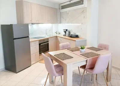 a kitchen with a table and chairs and a refrigerator at Amelie Apartment in Palaiochóra